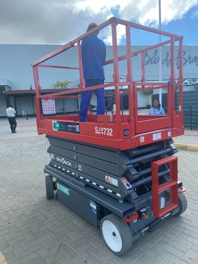 Plataforma tesoura vermelha com um operador na cesta, numa praça de shopping